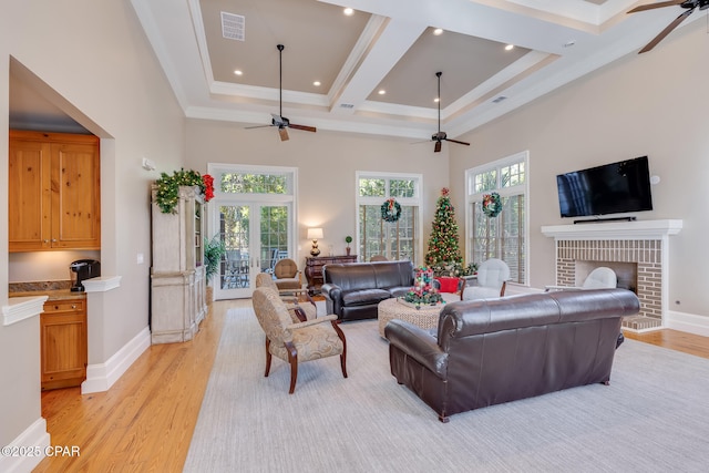 living room with a high ceiling, french doors, light hardwood / wood-style floors, a brick fireplace, and ornamental molding