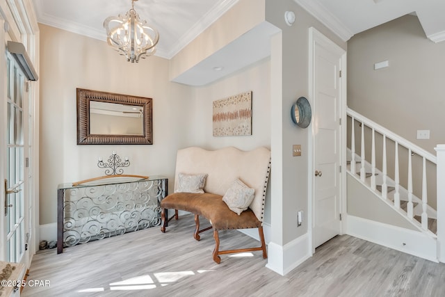 living area featuring light wood-type flooring, crown molding, and a chandelier