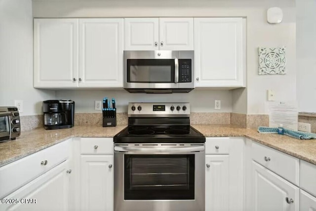 kitchen with light stone counters, white cabinets, and appliances with stainless steel finishes