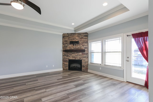 unfurnished living room with hardwood / wood-style floors, a fireplace, crown molding, and a tray ceiling