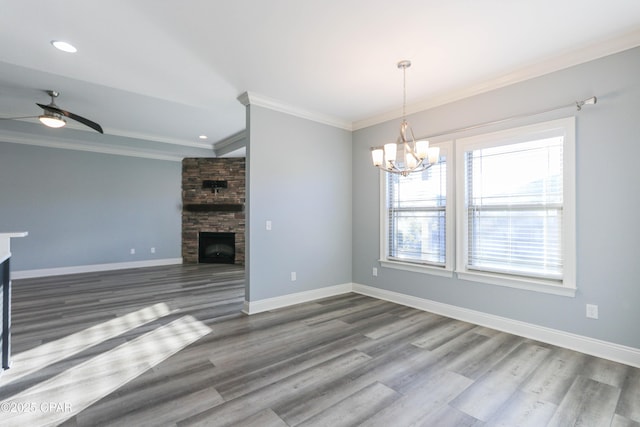 unfurnished living room with dark hardwood / wood-style floors, ornamental molding, a fireplace, and ceiling fan with notable chandelier