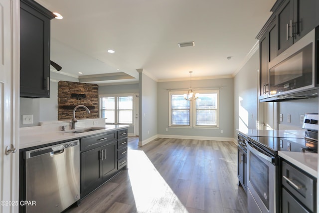 kitchen featuring appliances with stainless steel finishes, hanging light fixtures, ornamental molding, and sink