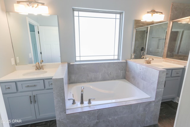 bathroom with tile patterned flooring, vanity, and tiled bath