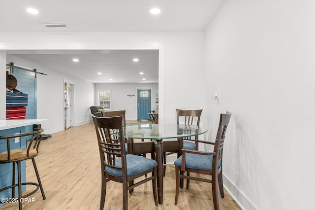 dining area featuring a barn door and light hardwood / wood-style flooring