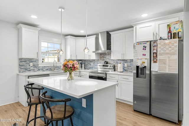 kitchen with wall chimney range hood, stainless steel appliances, and white cabinets