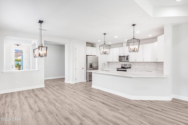 kitchen with white cabinets, sink, hanging light fixtures, decorative backsplash, and stainless steel appliances