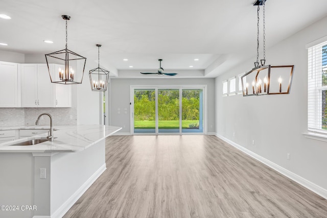 kitchen with white cabinetry, sink, ceiling fan, and hanging light fixtures