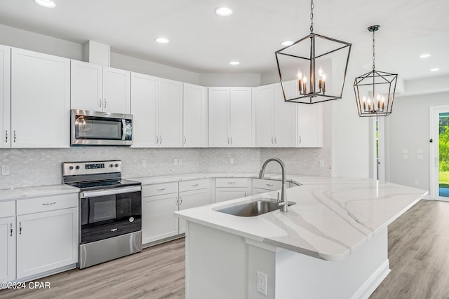 kitchen with white cabinets, sink, hanging light fixtures, kitchen peninsula, and stainless steel appliances