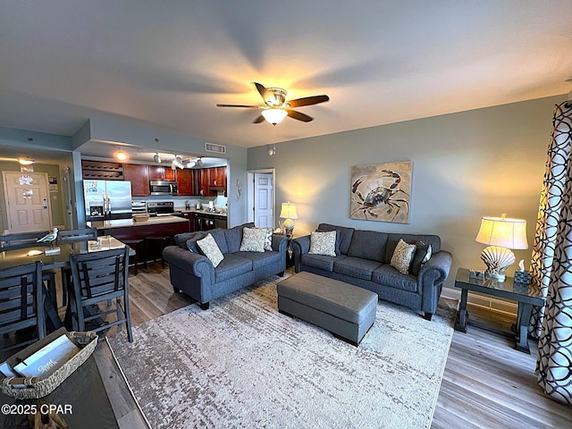 living room with light wood-type flooring and ceiling fan