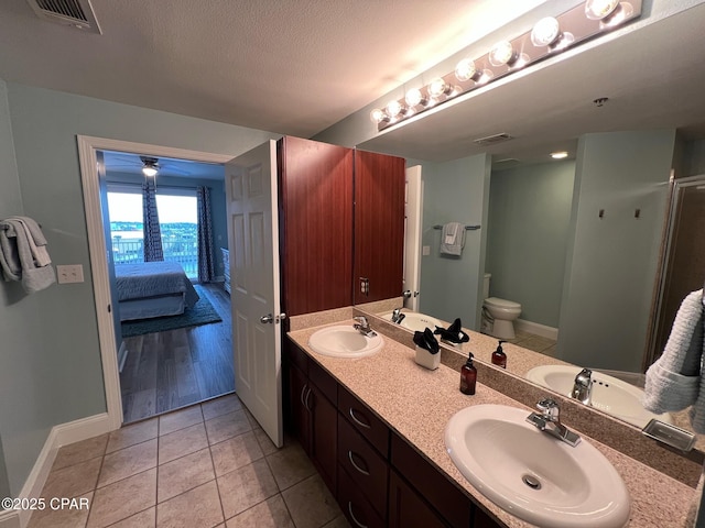 bathroom with tile patterned flooring, vanity, toilet, and a textured ceiling