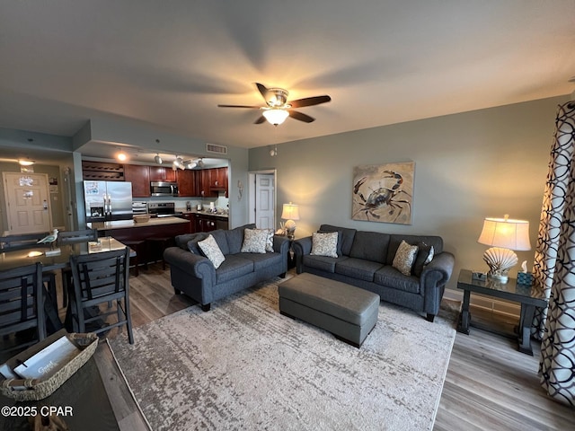 living room featuring ceiling fan and light hardwood / wood-style floors