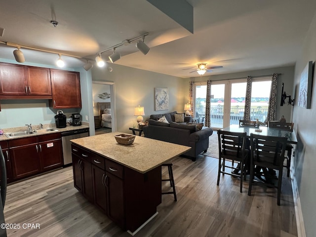 kitchen featuring sink, stainless steel dishwasher, ceiling fan, a kitchen island, and wood-type flooring