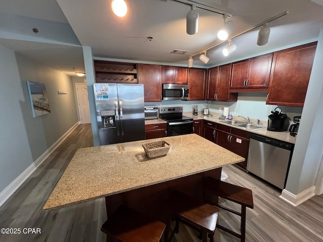 kitchen featuring a center island, a kitchen breakfast bar, sink, wood-type flooring, and stainless steel appliances