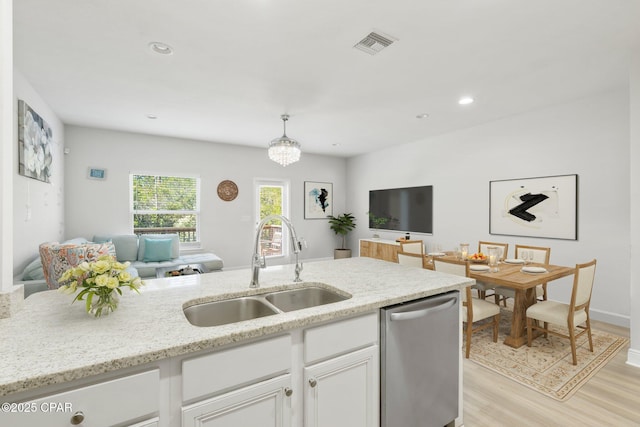 kitchen featuring decorative light fixtures, dishwasher, sink, white cabinets, and light stone counters