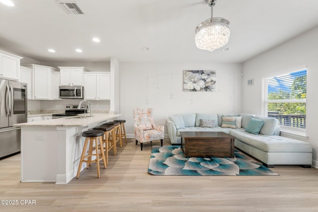 living room featuring a chandelier and light wood-type flooring