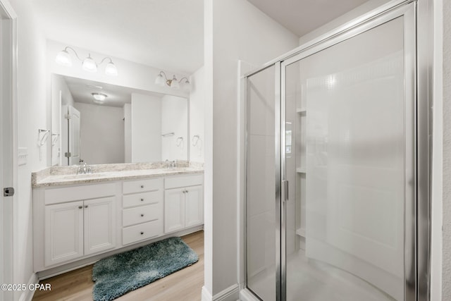 bathroom with vanity, a shower with shower door, and hardwood / wood-style floors