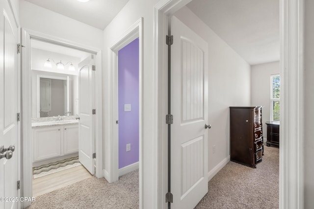 corridor featuring sink and light colored carpet