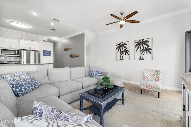 living room featuring ornamental molding, baseboards, and a ceiling fan