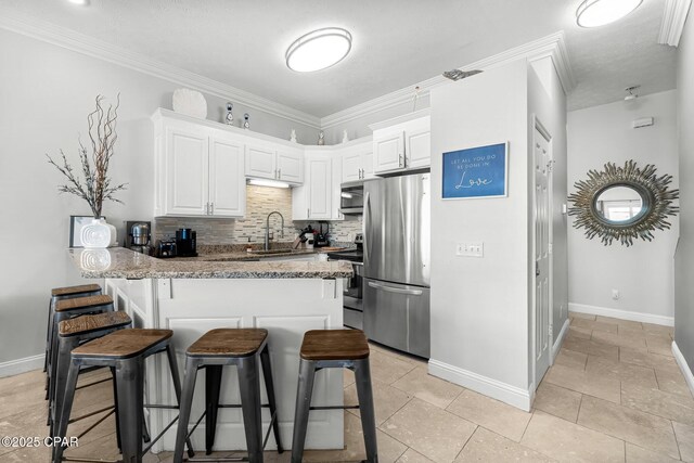 kitchen with sink, stainless steel appliances, light stone counters, kitchen peninsula, and white cabinets