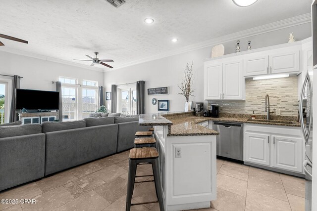 kitchen with a kitchen breakfast bar, stainless steel dishwasher, ceiling fan, sink, and white cabinets