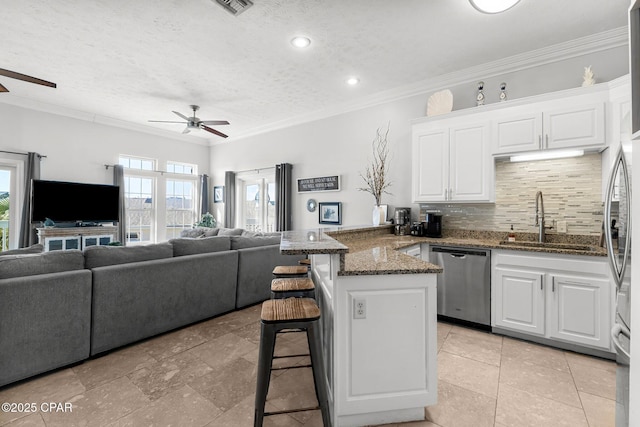 kitchen featuring dishwasher, a breakfast bar, open floor plan, a peninsula, and a sink