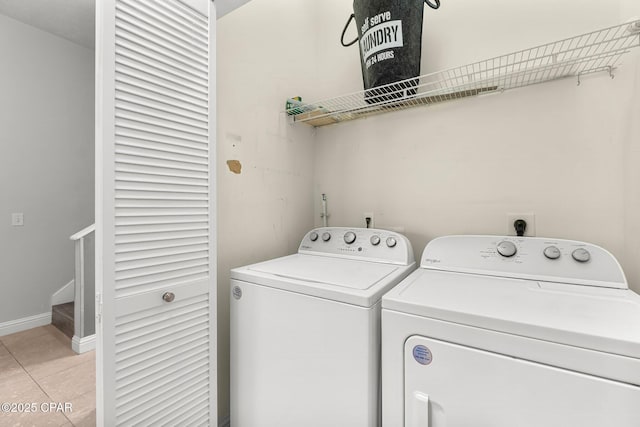 laundry area featuring light tile patterned floors, laundry area, washer and clothes dryer, and baseboards