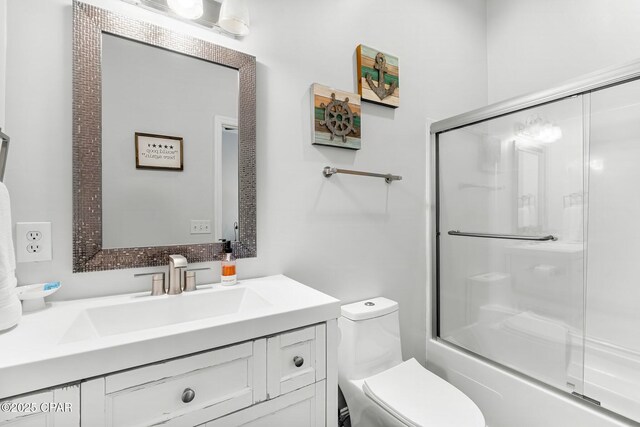 full bathroom with vanity, bath / shower combo with glass door, and toilet