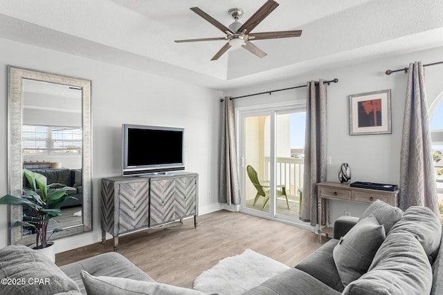 living room with plenty of natural light, wood finished floors, a ceiling fan, and baseboards