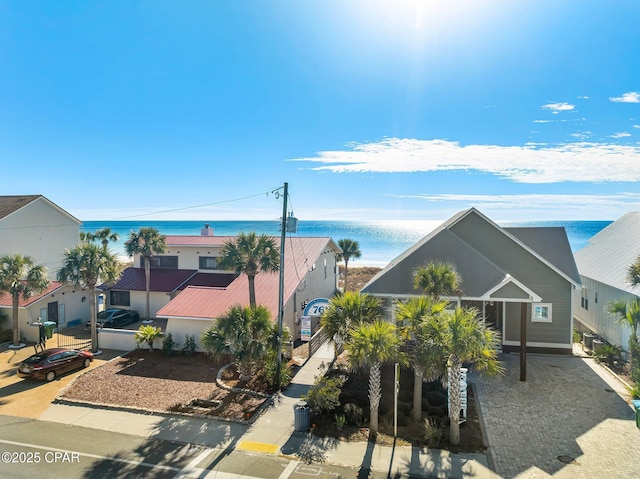 view of front of property featuring decorative driveway, a water view, and a residential view