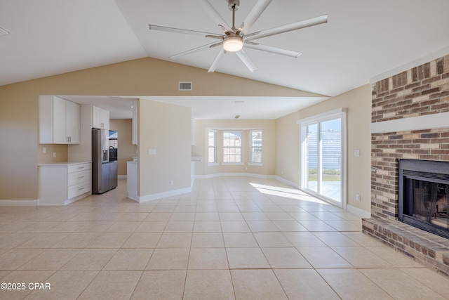 unfurnished living room featuring a fireplace, light tile patterned floors, ceiling fan, and lofted ceiling