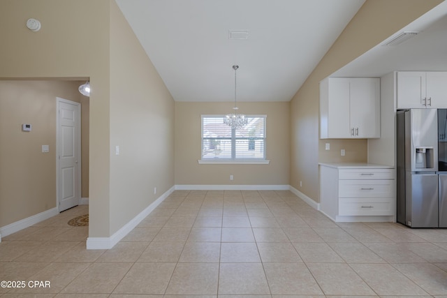 kitchen with white cabinetry, pendant lighting, stainless steel fridge, and vaulted ceiling