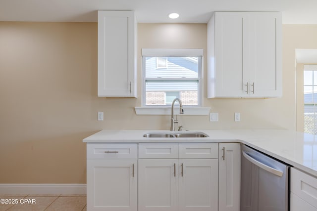 kitchen featuring sink, light tile patterned floors, light stone counters, white cabinets, and stainless steel dishwasher