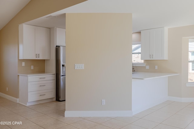 kitchen with white cabinetry, vaulted ceiling, light tile patterned flooring, and stainless steel fridge with ice dispenser