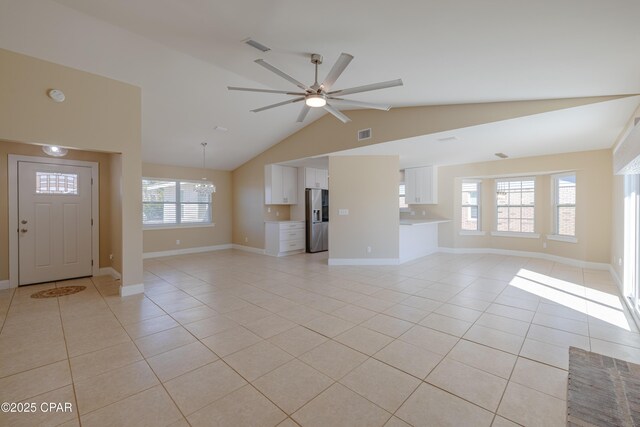 unfurnished living room featuring ceiling fan with notable chandelier, lofted ceiling, light tile patterned floors, and a brick fireplace