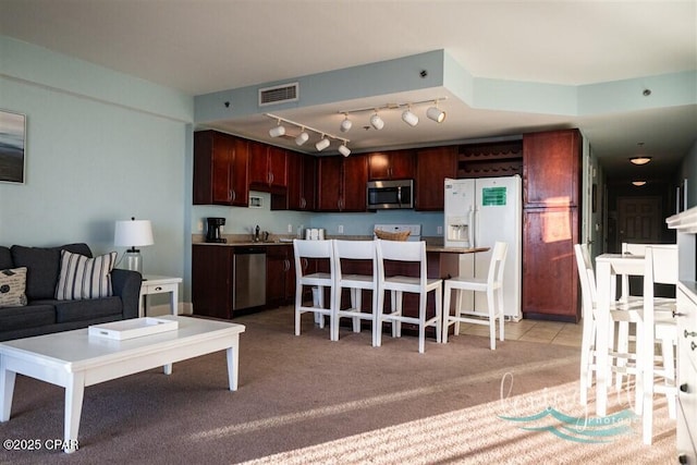 kitchen with a breakfast bar area, a center island, light colored carpet, and appliances with stainless steel finishes