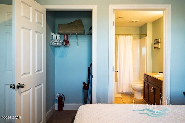 bedroom with ensuite bath, light tile patterned floors, and a closet