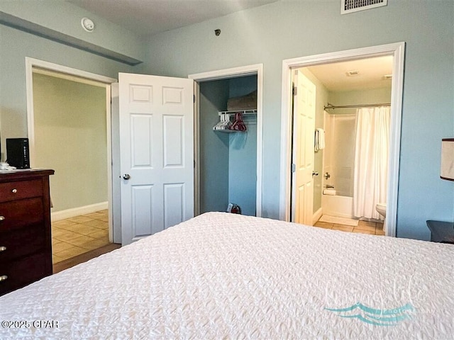 bedroom with a walk in closet, ensuite bathroom, a closet, and light tile patterned flooring