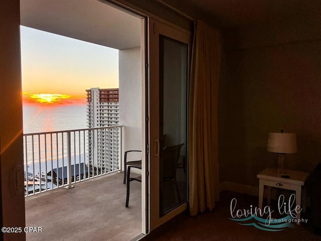 balcony at dusk featuring a water view