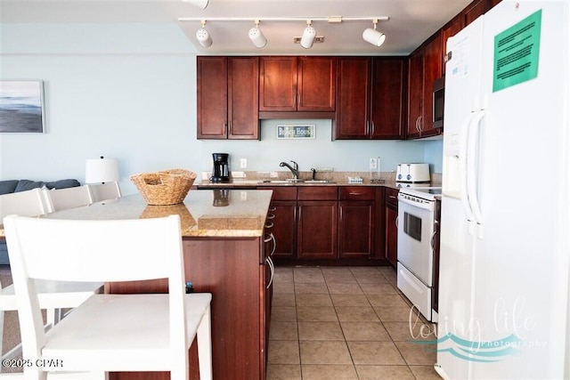 kitchen featuring light stone countertops, white appliances, sink, light tile patterned floors, and a kitchen island