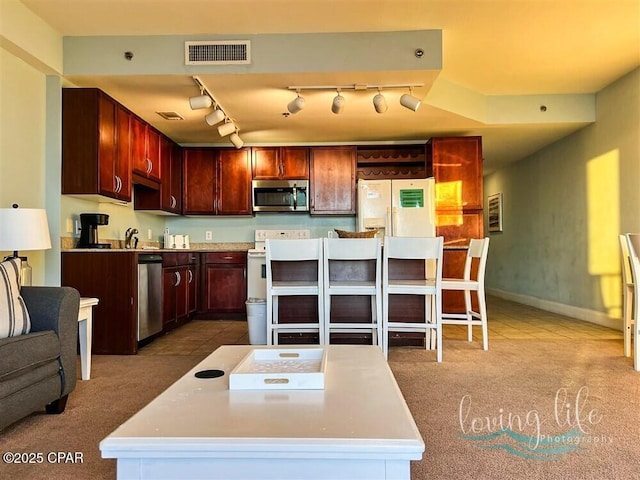 kitchen featuring a center island, carpet, stainless steel appliances, and track lighting