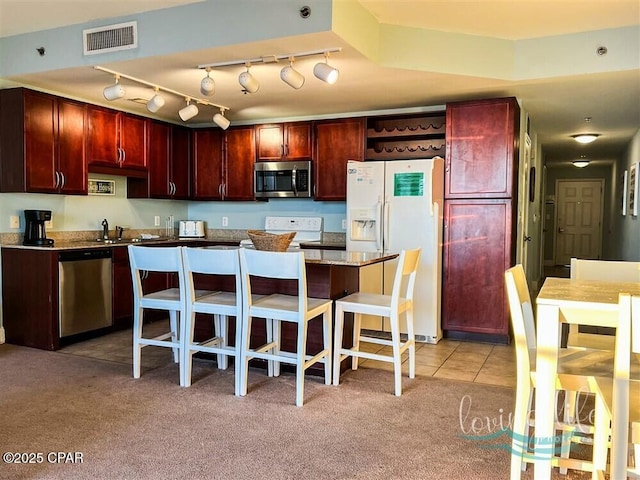 kitchen featuring appliances with stainless steel finishes, a center island, light colored carpet, and a breakfast bar area