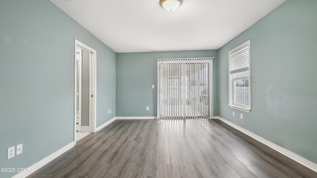 spare room with a textured ceiling and dark hardwood / wood-style floors