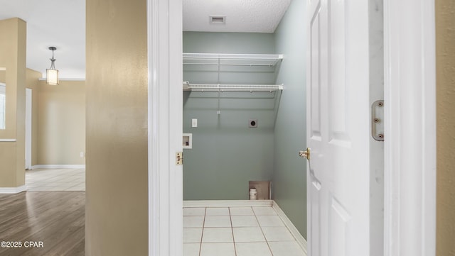 laundry area featuring hookup for a washing machine, a textured ceiling, light tile patterned floors, and electric dryer hookup