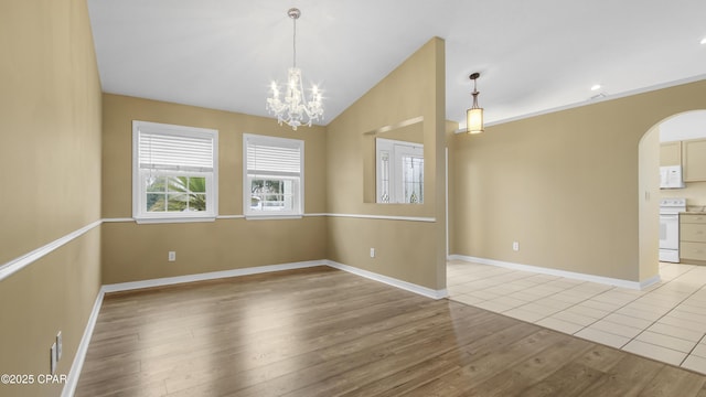 empty room featuring light wood-type flooring, vaulted ceiling, and a chandelier