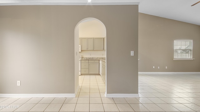 empty room featuring ceiling fan, lofted ceiling, and light tile patterned flooring