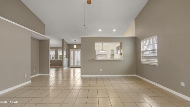 unfurnished living room with light tile patterned flooring, lofted ceiling, and ceiling fan with notable chandelier