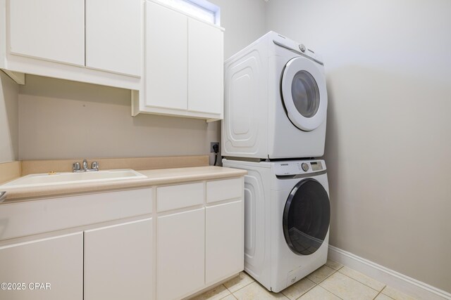 laundry room with cabinets, stacked washing maching and dryer, sink, and light tile patterned floors