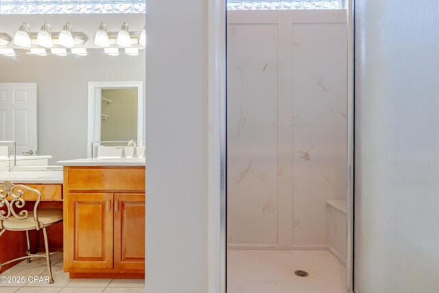 bathroom with a shower with door, vanity, and tile patterned flooring