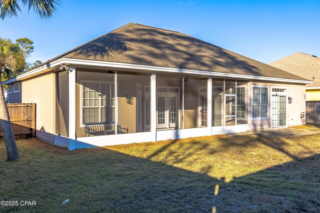 back of house with a sunroom and a lawn