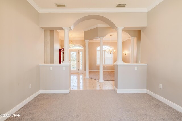 carpeted spare room with ornamental molding, a chandelier, and decorative columns